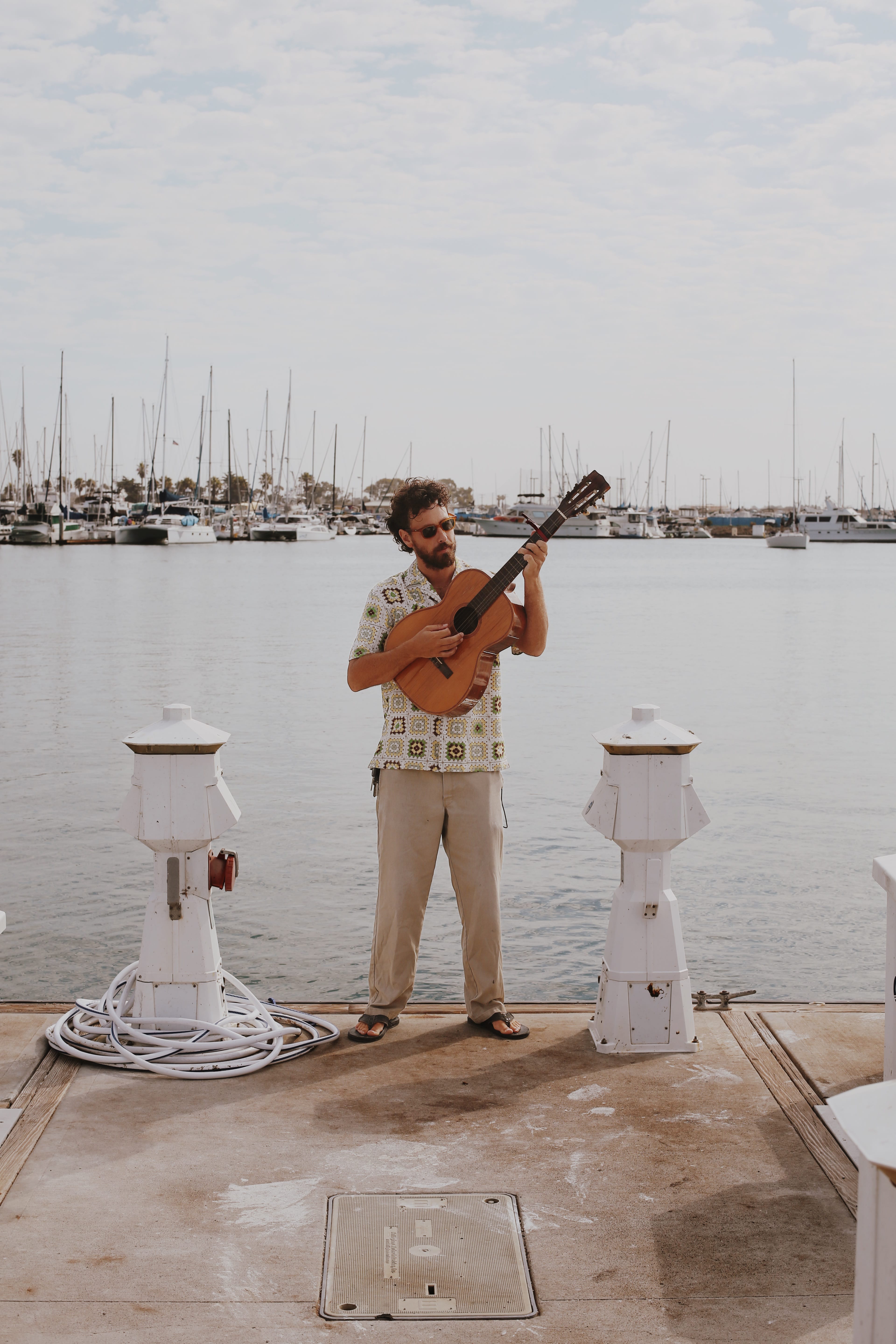 Musical Artist Alec Ledbetter standing on a dock holding a guitar